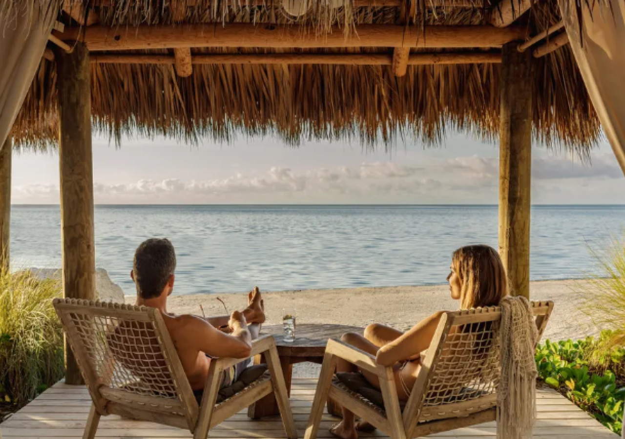 A couple sits at an oceanfront cabana