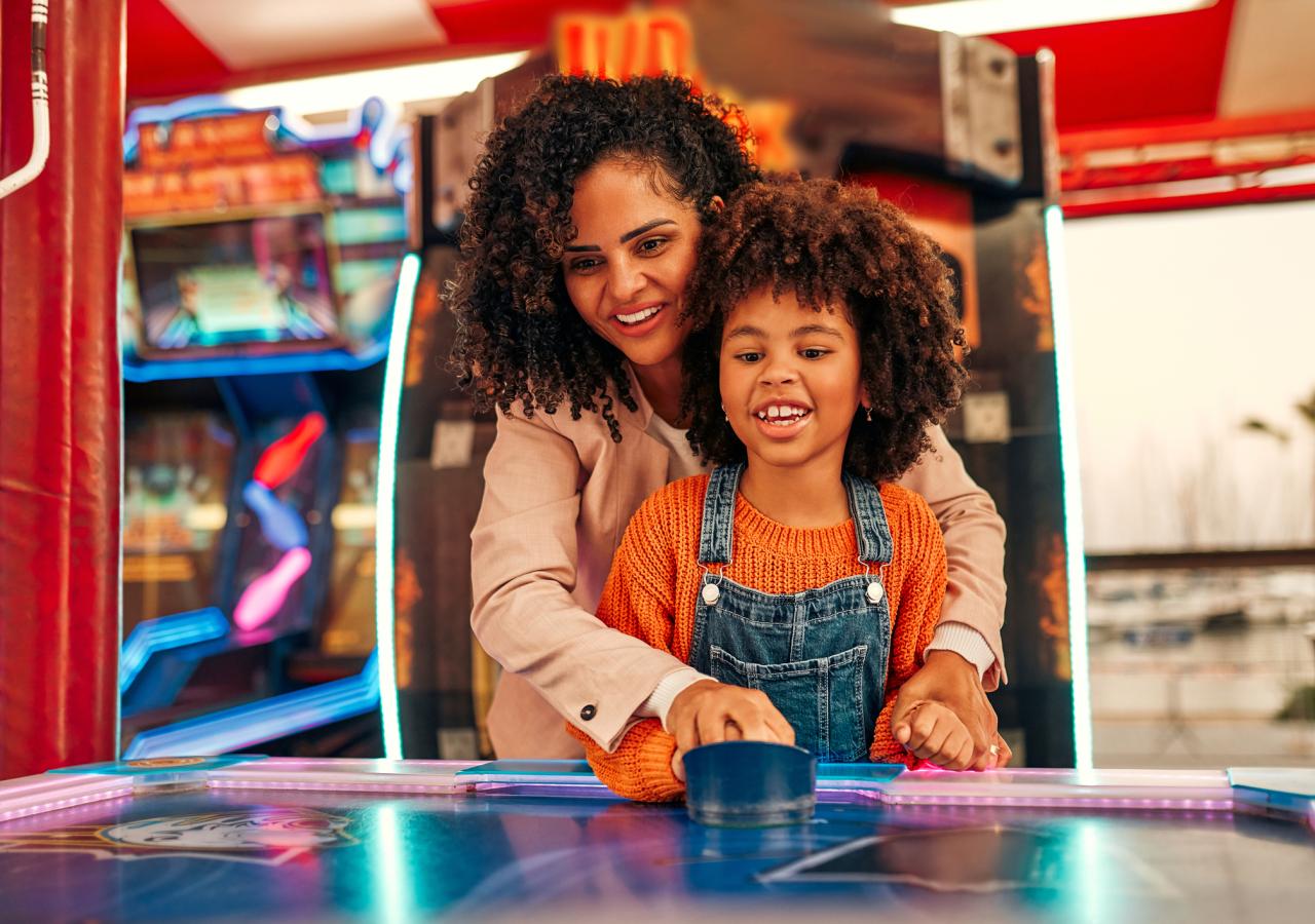 A mom and her kid playing in an arcade.