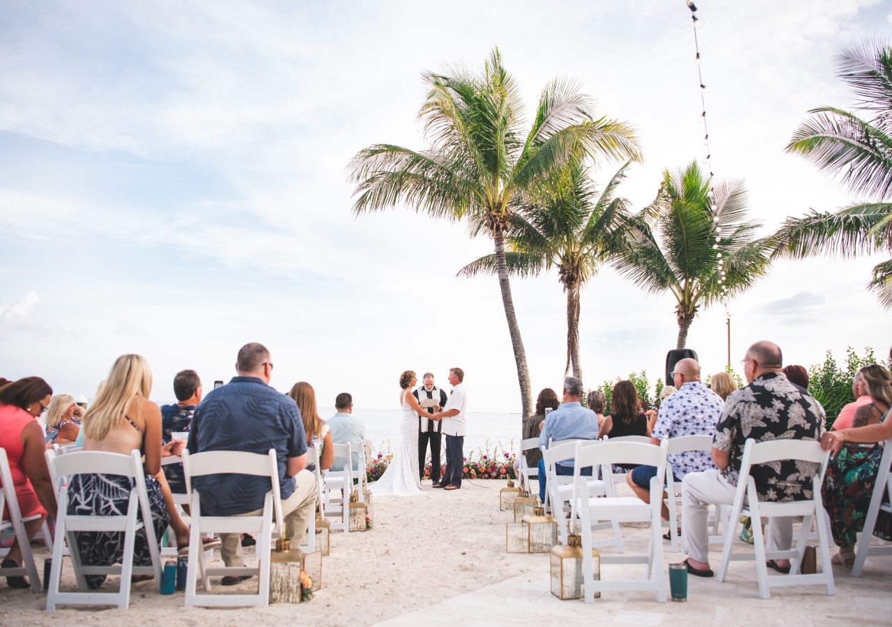 Wedding on the beach, couple is holding hands infront of their wedding guests