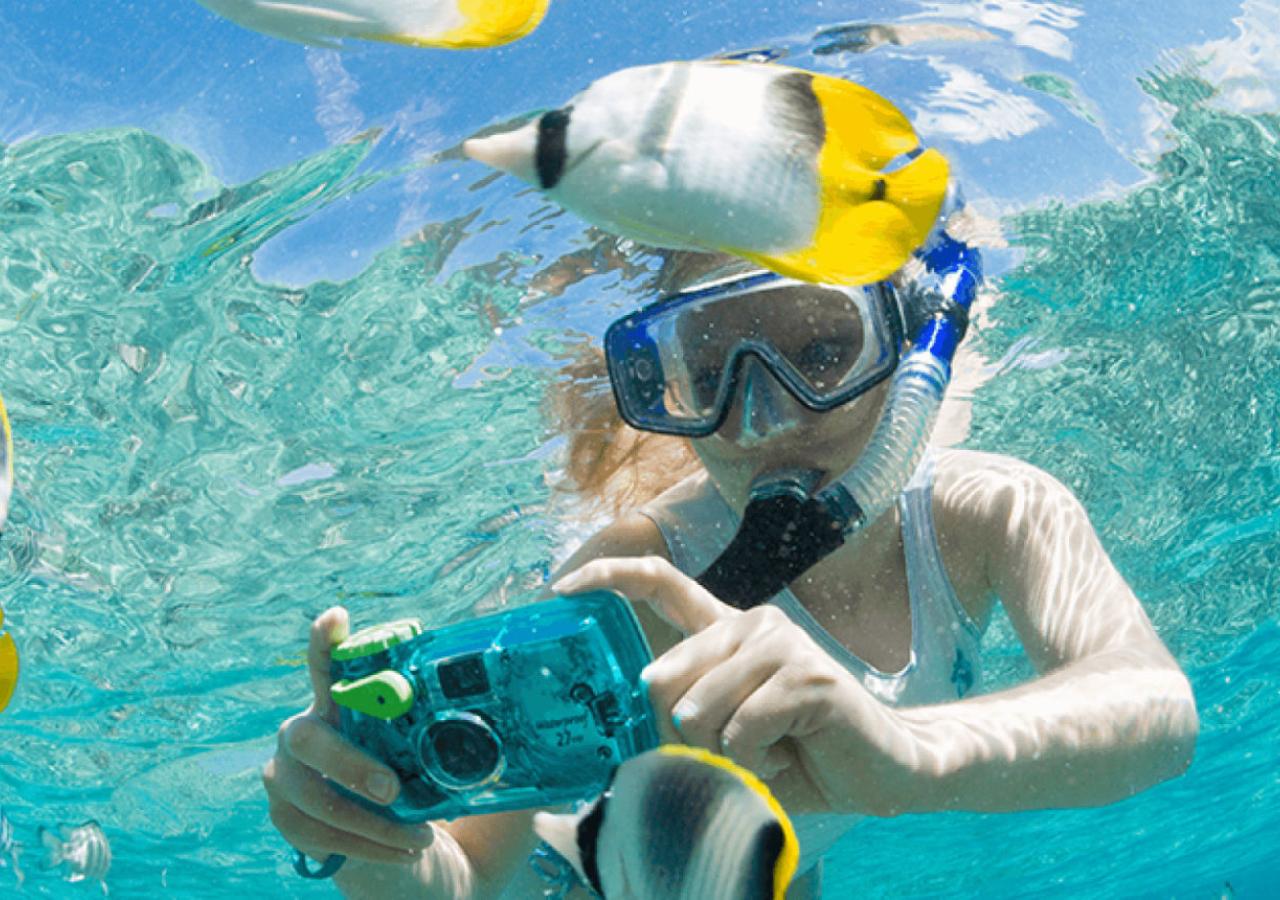 Woman snorkeling and taking photos of fish