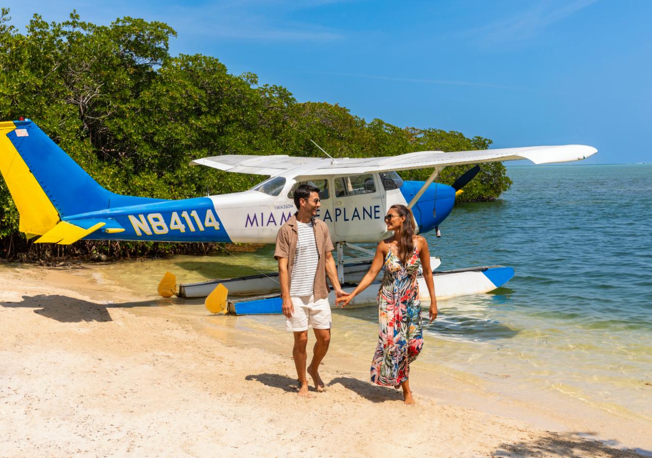 Two people on a beach with a plane in the background in the water