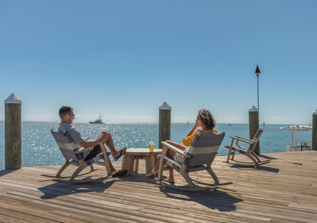 couple sitting on chairs on a dock by the ocean