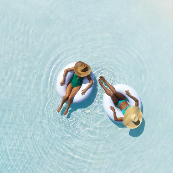 Two women are floating in the pool.