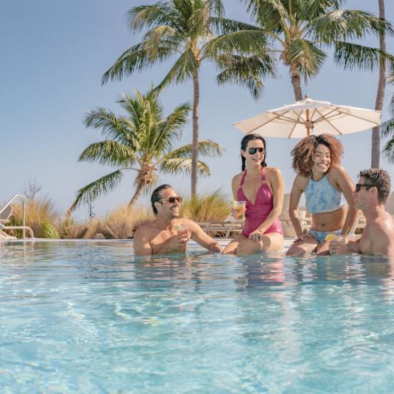 Friends sit by the pool on a sunny day at Amara Cay