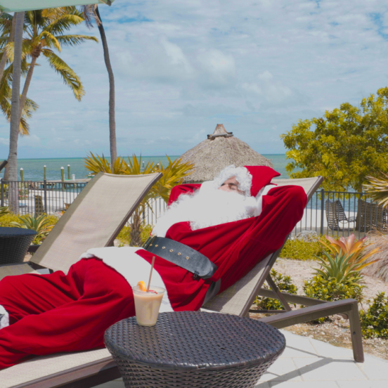 Santa laying on a chaise lounge by the pool.