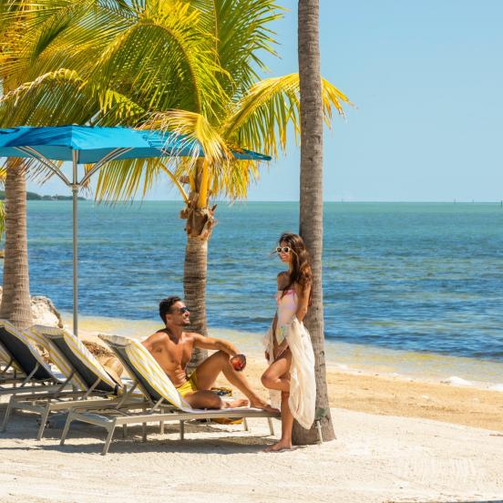 A couple smiles at each other while on a beach at Three Waters Resort