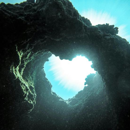 A heart shape out of a rock in the ocean.